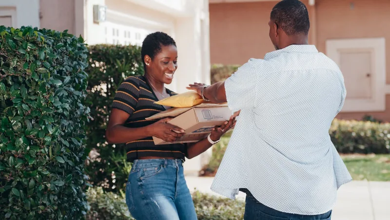 Smiling woman receiving several delivered packages outdoors